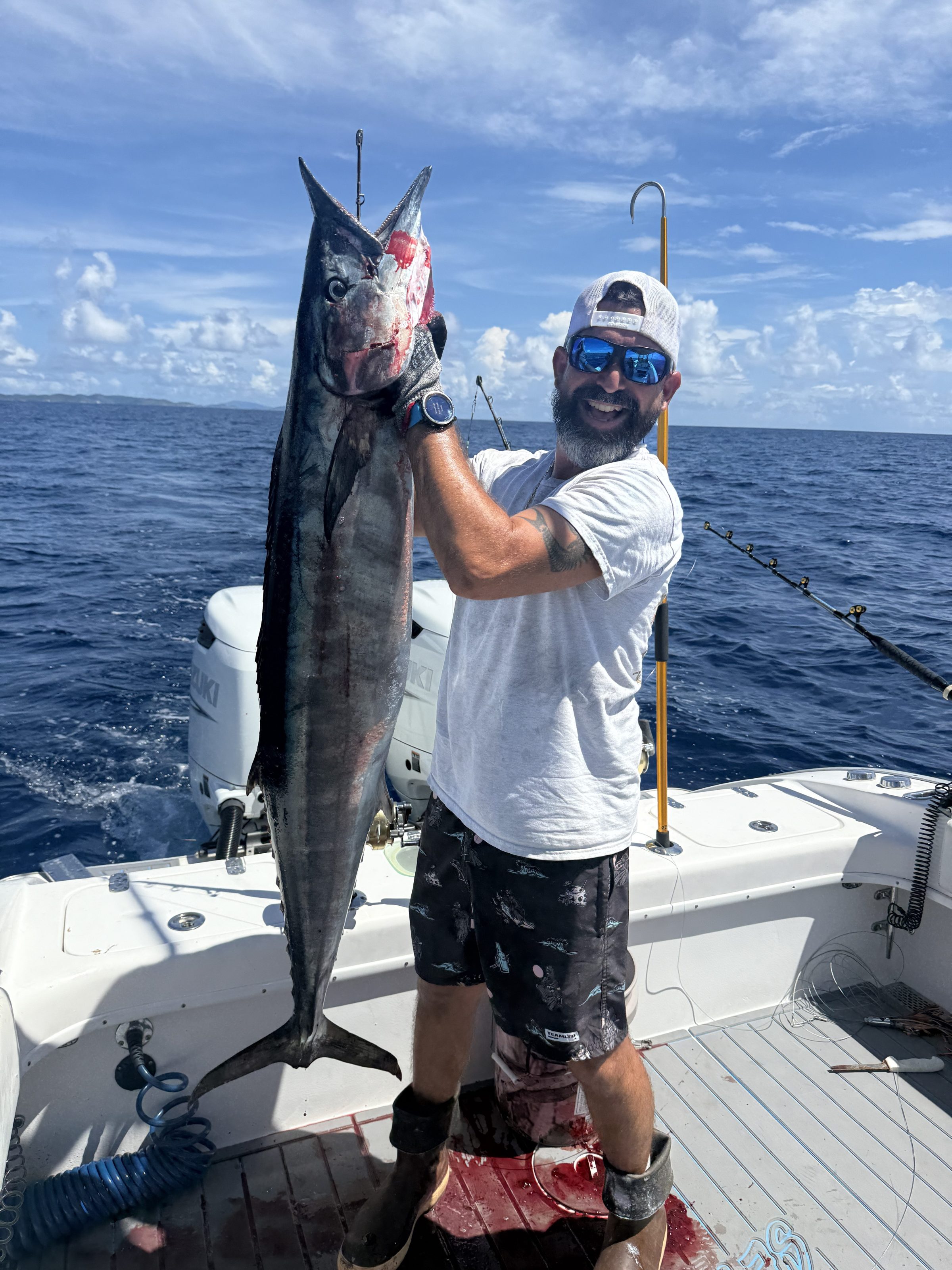 Person on a boat holding a large fish with the ocean in the background.