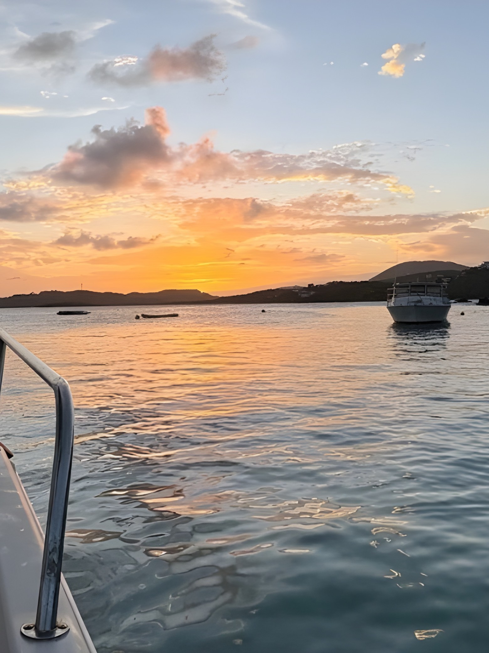 Boat on calm water at sunset with distant islands.