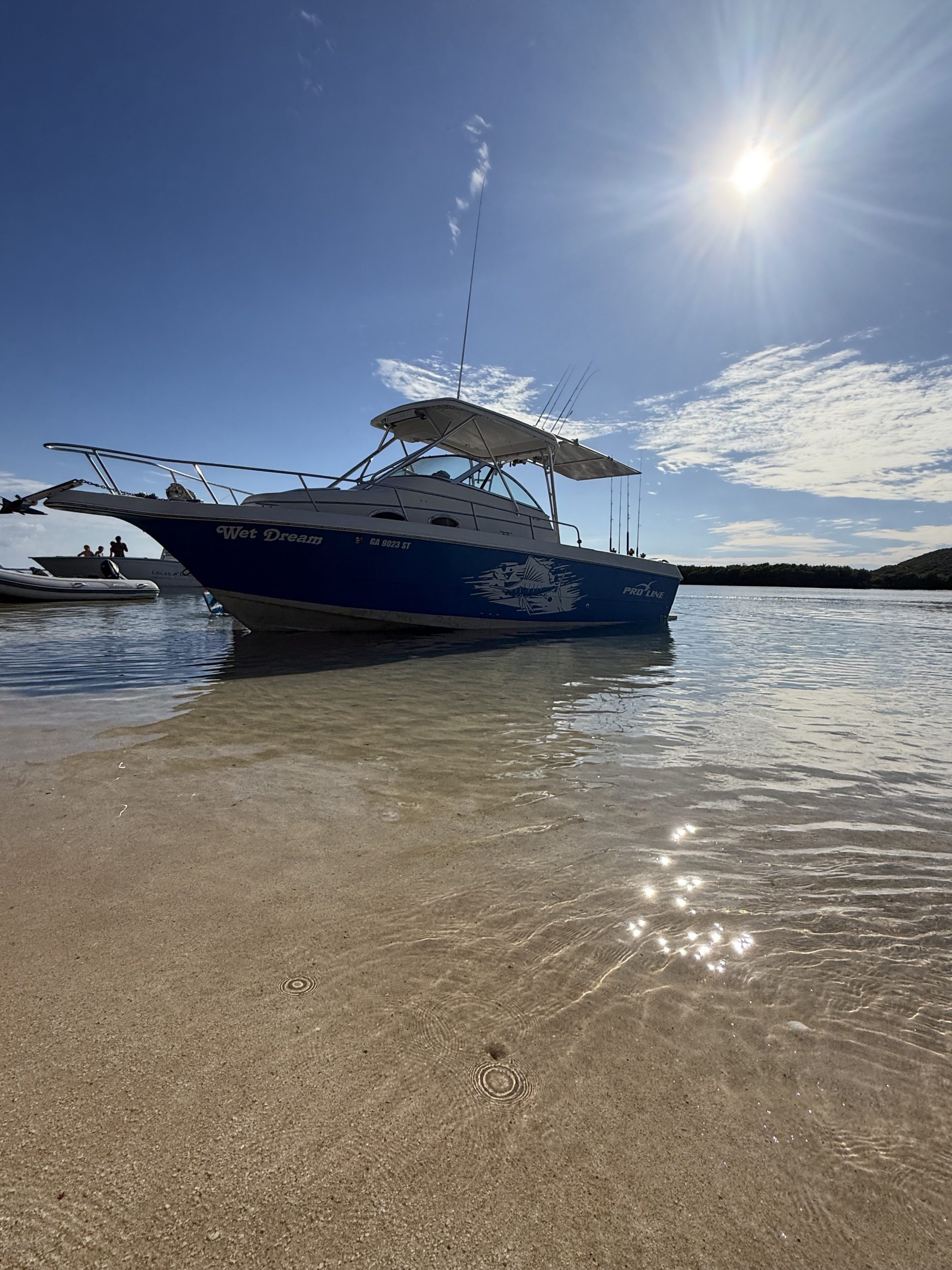 Boat on sunlit beach with clear sky and calm water.